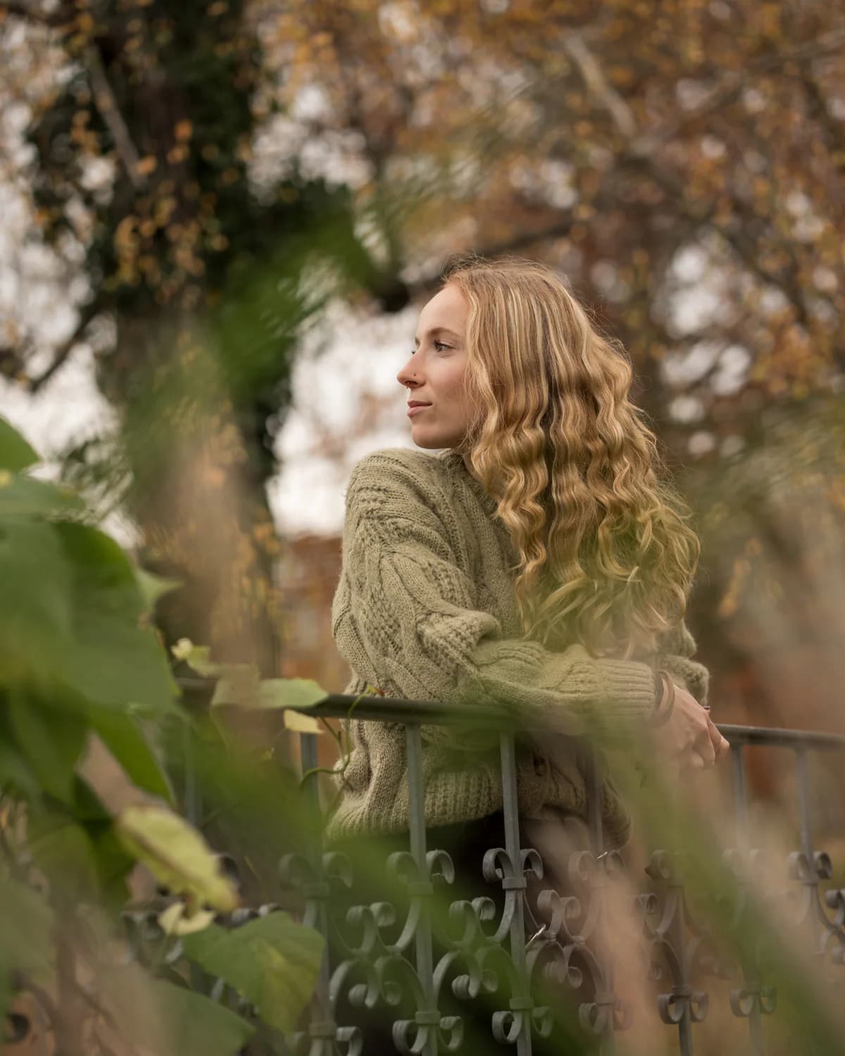 Lily lehnt zwischen herbstlichen Zweigen an einem Geländer