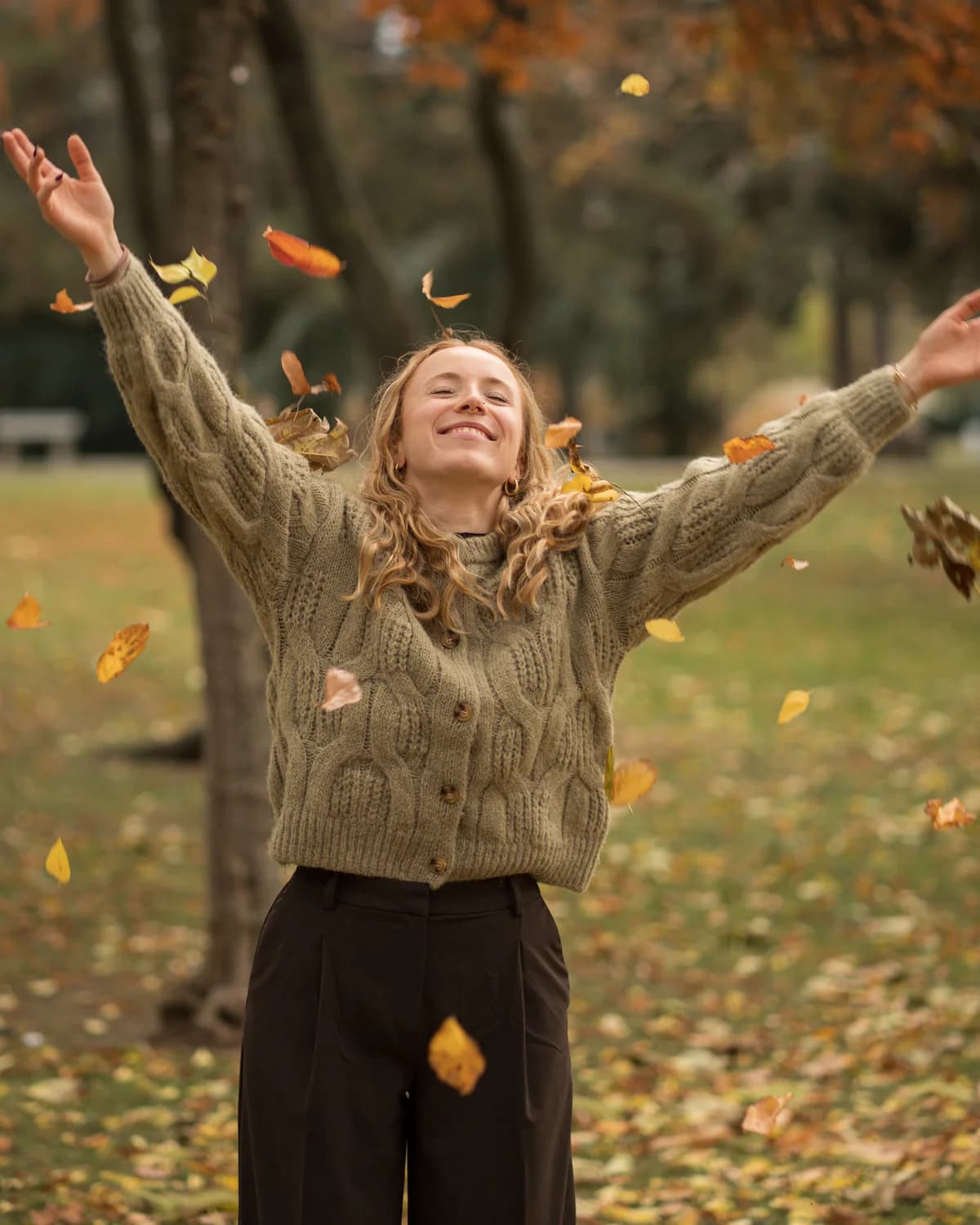 Lily wirft lachend Herbstblätter in die Luft