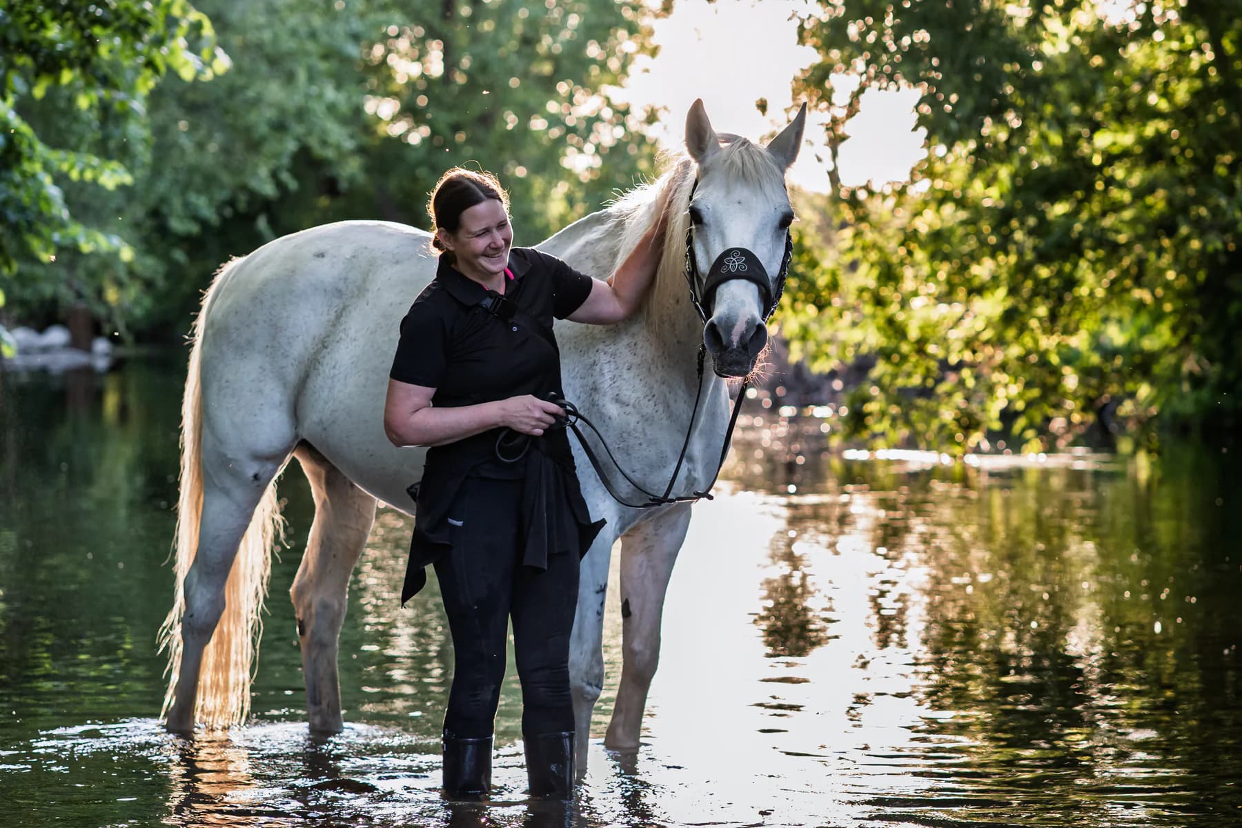 Sophie mit weißem Pferd im Wasser und warmem Gegenlicht